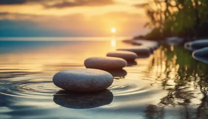 Smooth stones aligned in calm water at sunset.